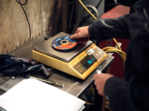 Grinding wheel being weighed during abrasive performance testing